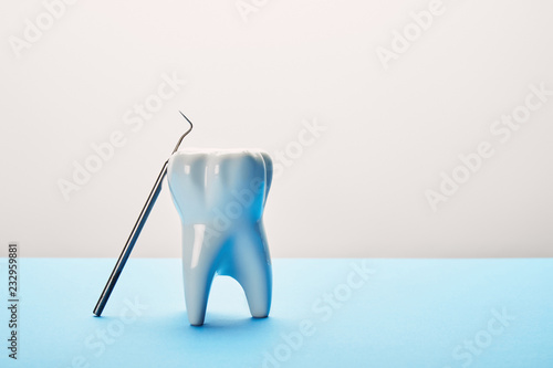 close up view of tooth model and dental probe on blue and white background