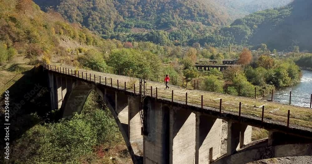 pictorial aerial view tourist walks on ruined railroad bridge over blue river running in ghost town among forestry hills pictorial aerial view tourist walks on ruined railroad bridge over blue river running in ghost town among forestry hills