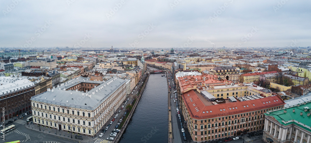 Autumn cloudy day with view of rooftops; different architecture style houses, mansions with cultural history; popular touristic water rout in Saint Petersburg with usual foggy cityscape and channels