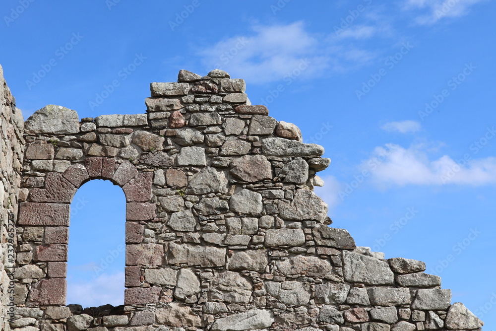 Window opening in old stone wall against blue  sky