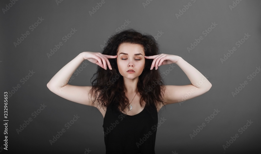 Portrait of a girl on a dark background.  Holds the fingers of the head