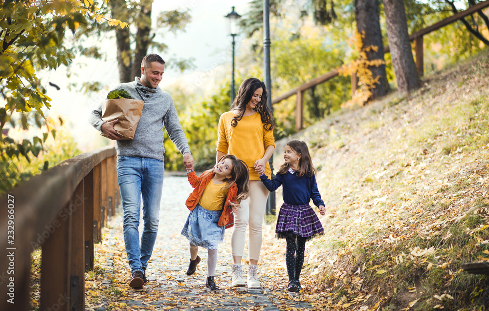 A young family with children walking in park in autumn. A young family with children walking in park in autumn.