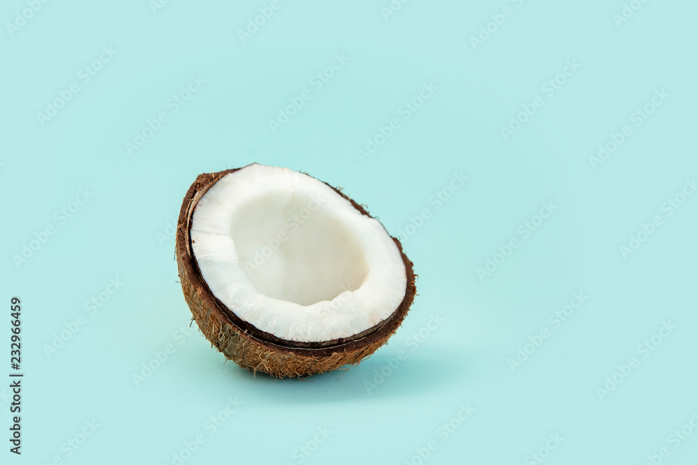 one half of ripe coconut on blue background - obrazy, fototapety, plakaty 