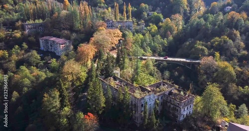 bird-eye-flight above roofless multi-storey houses in ghost town among picturesque autumn trees on sunny day photo