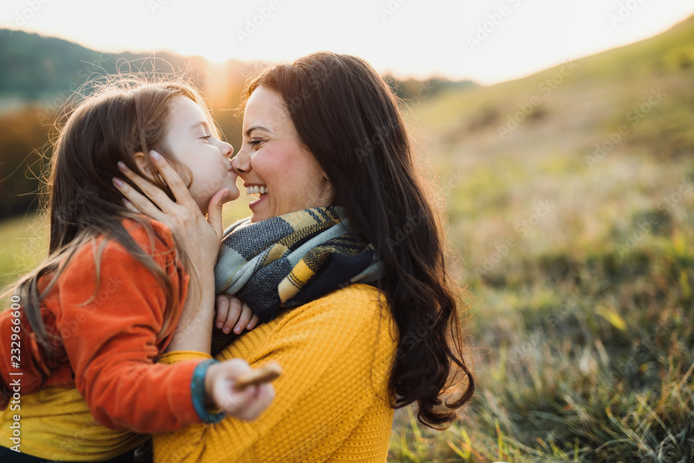 A portrait of young mother with a small daughter in autumn nature at sunset. A portrait of young mother with a small daughter in autumn nature at sunset.