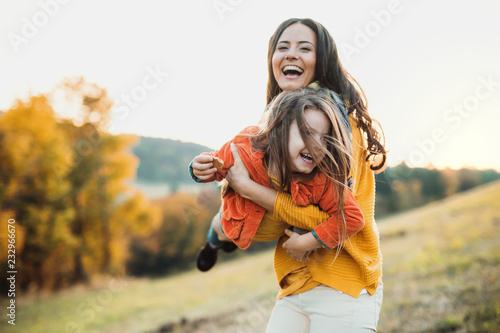 Fotografia A portrait of young mother with a small daughter in autumn nature at sunset