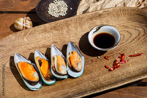 Delicious seafood mussels with sauce, red pepper and parsley. Clams in the shells on a wooden table
 photo