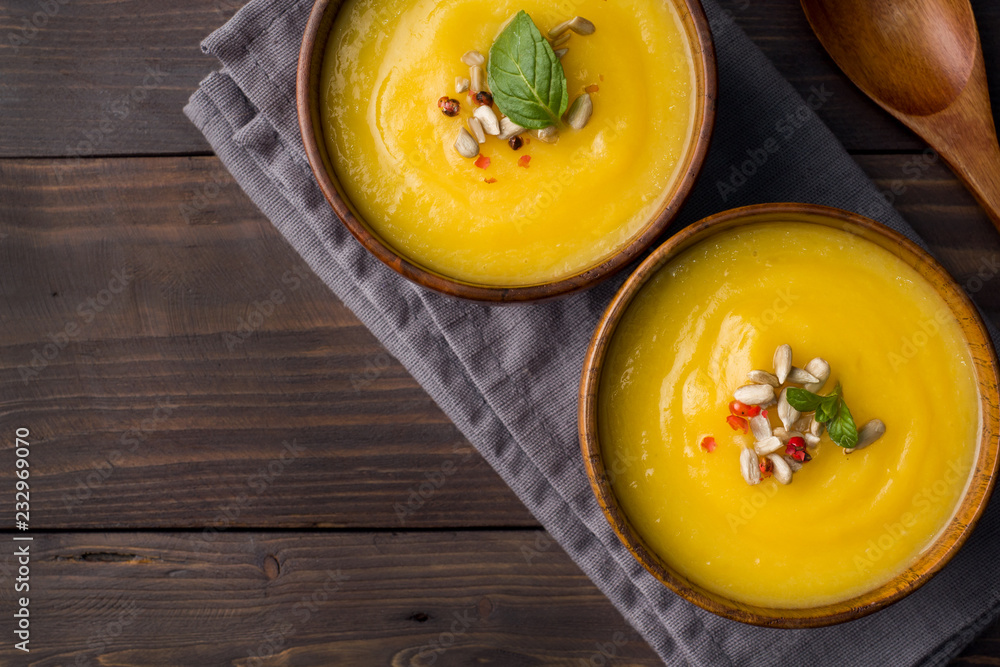 Pumpkin soup mashed with spices in wooden bowls on dark boards. Pumpkin soup mashed with spices in wooden bowls on dark boards.