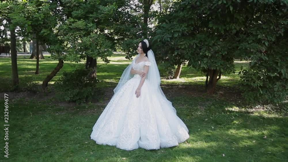 A very beautiful bride stands alone in the park, worries while waiting for the groom A very beautiful bride stands alone in the park, worries while waiting for the groom