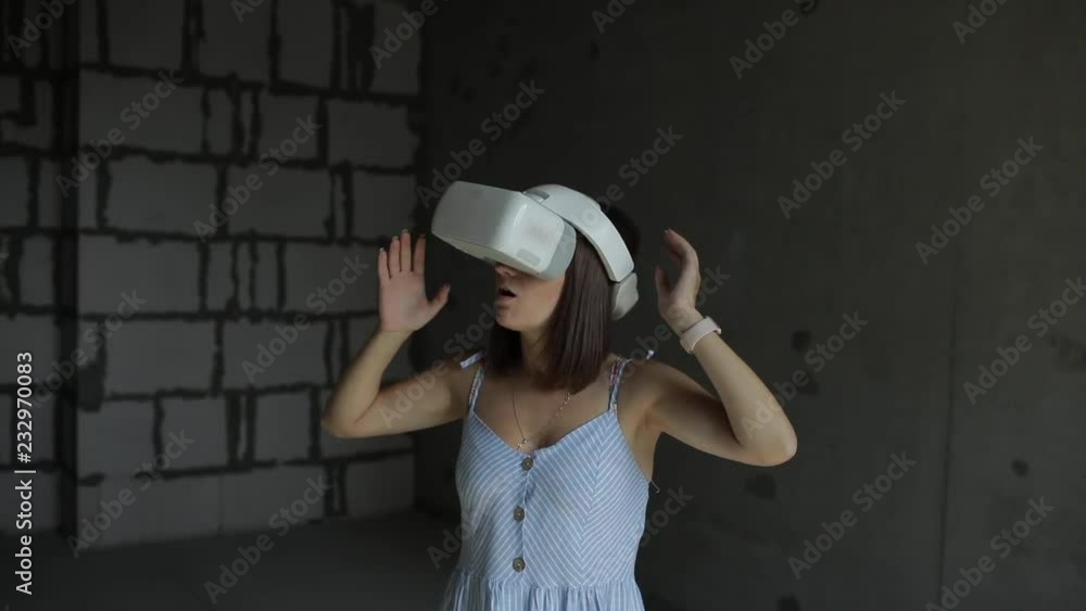 Young woman in virtual reality (VR) glasses. Isolated on construction background Young woman in virtual reality (VR) glasses. Isolated on construction background