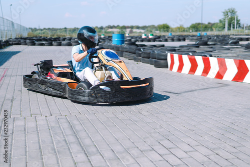 Go-Kart racing car on the track in action, championship, active sports, extreme fun, the driver keeps his hands on the wheel. driver protective gear. day, karting © Sergey