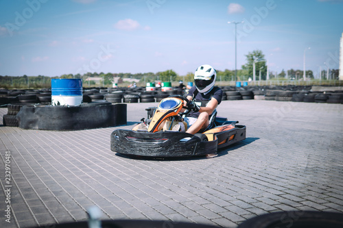 Go-Kart racing car on the track in action, championship, active sports, extreme fun, the driver keeps his hands on the wheel. driver protective gear. day, karting