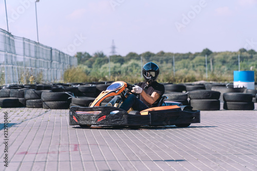 Go-Kart racing car on the track in action  championship  active sports  extreme fun  the driver keeps his hands on the wheel. driver protective gear. day  karting