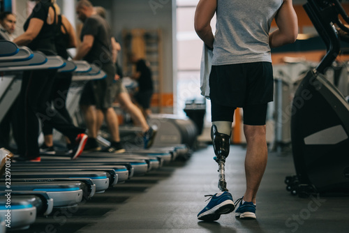 cropped shot of athletic sportsman with artificial leg walking by gym photo