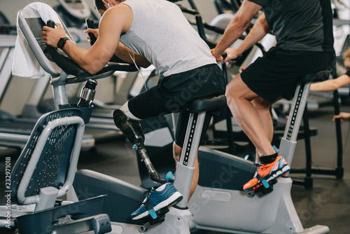 sportsman with artificial leg working out on stationary bicycle at gym