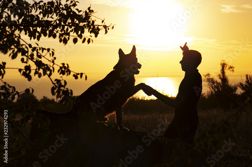 silhouette of man and dog enjoying beautiful landscape , boy with pet at sunset, concept of harmony human and nature, happiness © fantom_rd