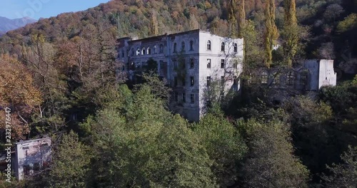 camera rises along green trees above ruined ghost town shows pictorial autumn forest on hill against distant mountains  photo