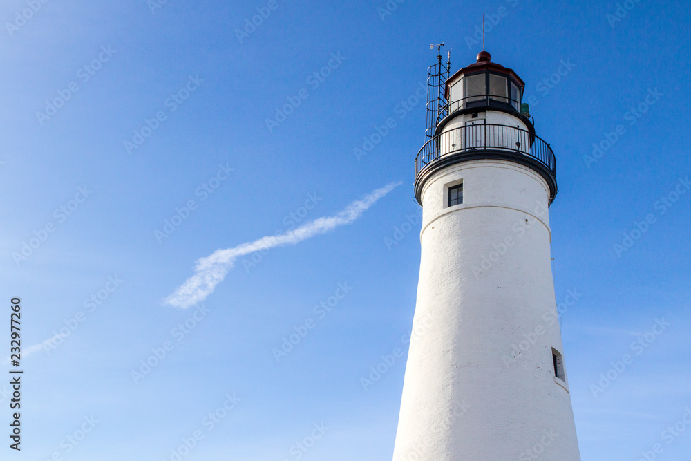 White Lighthouse Tower With Copy Space. The Fort Gratiot Lighthouse in Port Huron, Michigan shot under sunny blue sky with copy space. The lighthouse is the oldest active light on the Great Lakes. 