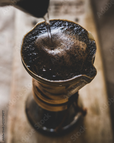 Water being poured from a kettle over grinded coffebeans photo