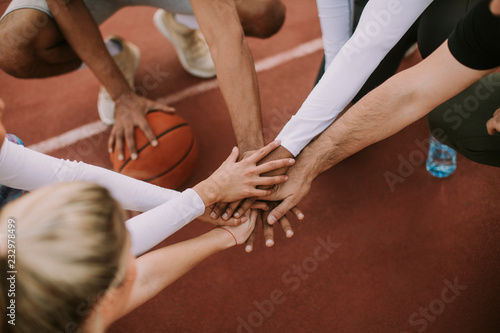 Fototapeta Naklejka Na Ścianę i Meble -  Top view of basketball team holding hands over court