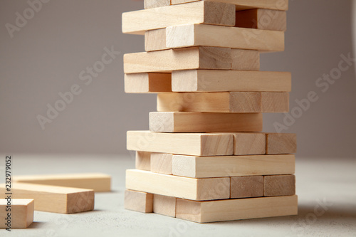 Tower of wooden blocks on gray background. Board game for the whole family or party. Concept of building business or building team.