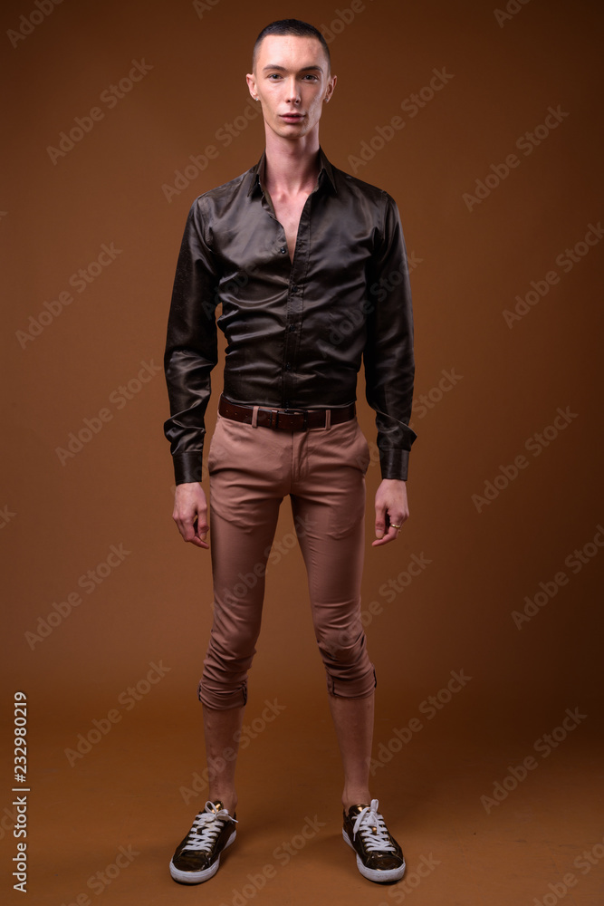 Young handsome androgynous businessman against brown background Young handsome androgynous businessman against brown background
