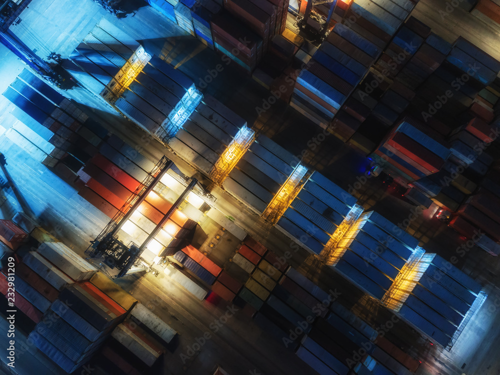 Fototapeta premium Aerial view container in container warehouse at sea port and working crane bridge loading container for logistics import export or transportation concept background.