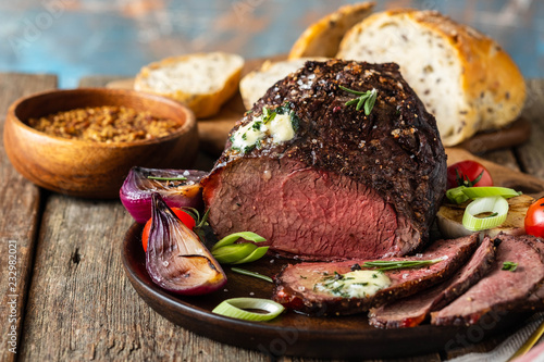 Roast beef on cutting board. Wooden background. Copy space.