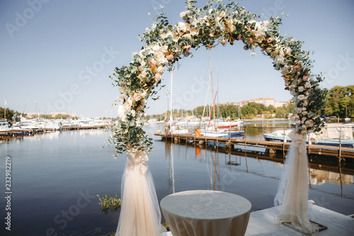 Arch decorated with flowers for the wedding ceremony in the yacht club
