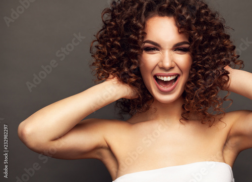 Fashion studio portrait of beautiful smiling woman with afro curls hairstyle. Fashion and beauty.