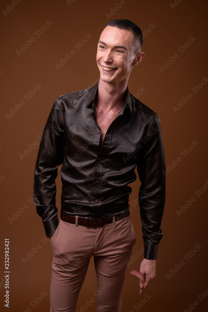 Young handsome androgynous businessman against brown background