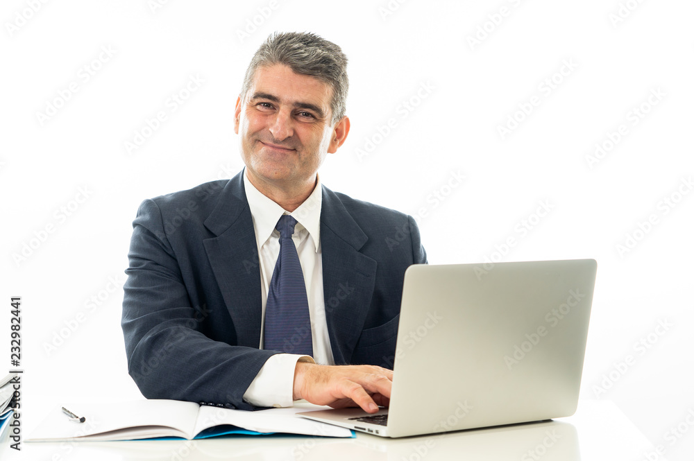Attractive happy mature caucasian businessman working on laptop computer on desk at office Attractive happy mature caucasian businessman working on laptop computer on desk at office