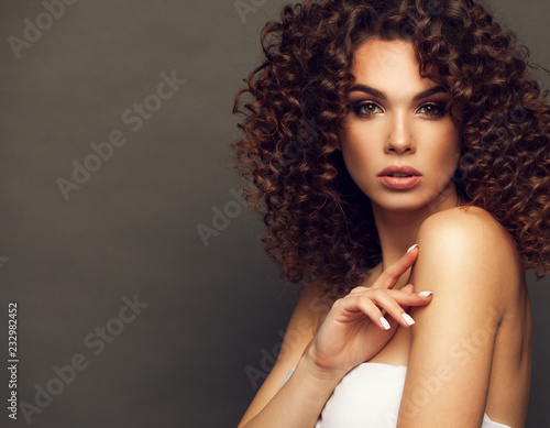 Fashion studio portrait of beautiful smiling woman with afro curls hairstyle. Fashion and beauty.