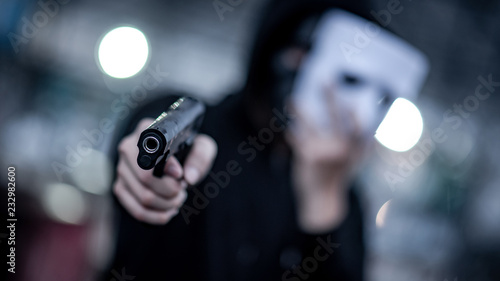 Canvas Print Mystery hoodie man in white mask pointing gun