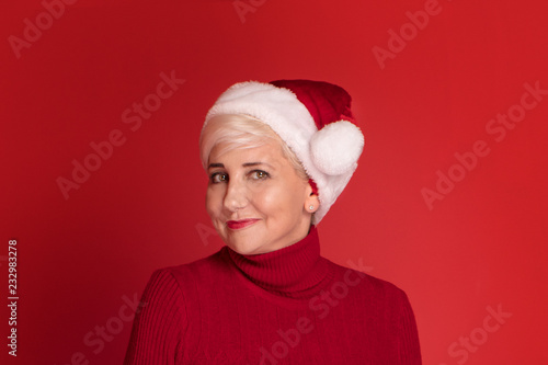 Smiling mature woman in red santa claus hat.
