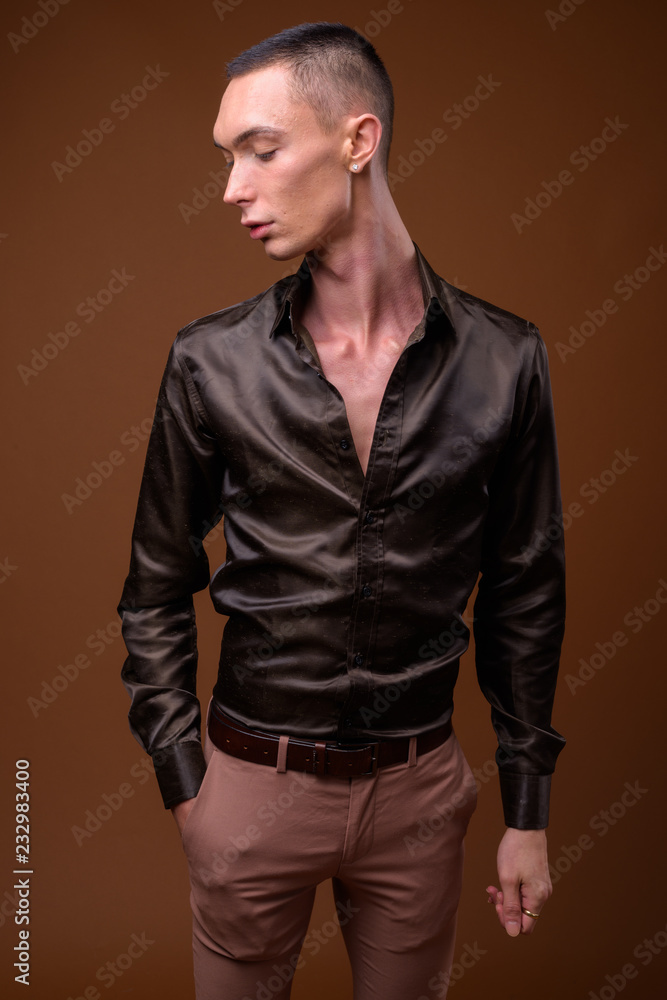 Fototapeta premium Young handsome androgynous businessman against brown background