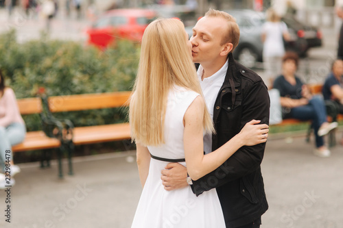 Handsome man kiss her lovely wife. Beautiful woman in white dress hug his husband © Aleksandr