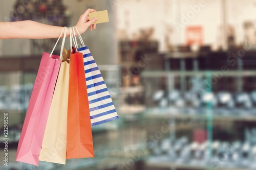 Woman with shopping bags and card on mall background