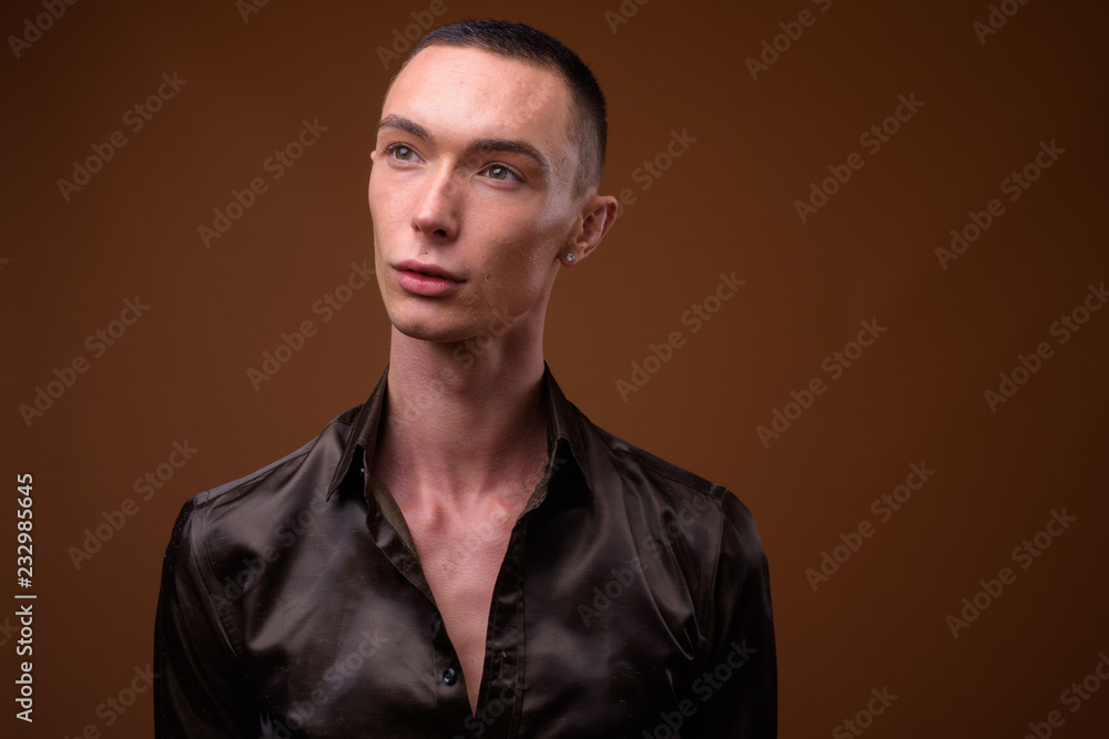 Obraz premium Young handsome androgynous businessman against brown background