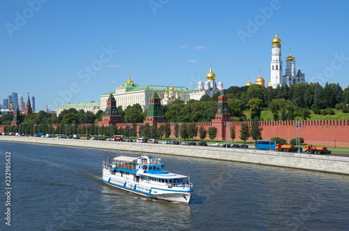 Summer view of the Moscow Kremlin and the Kremlin embankment, Russia. Pleasure boat floats past the walls of the Kremlin