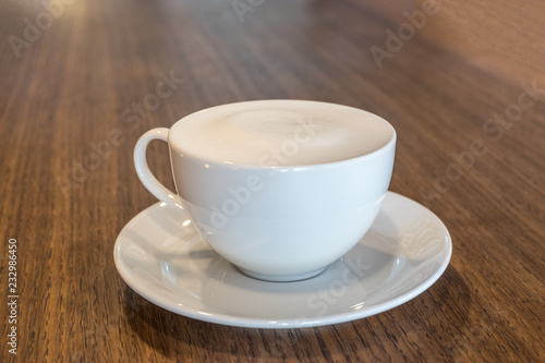 A cup of coffee with milk froth on wooden table background