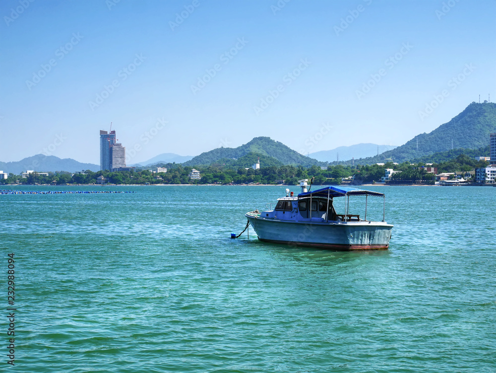 Small Boat Floating in the Sea with Mountain and City on Background Small Boat Floating in the Sea with Mountain and City on Background