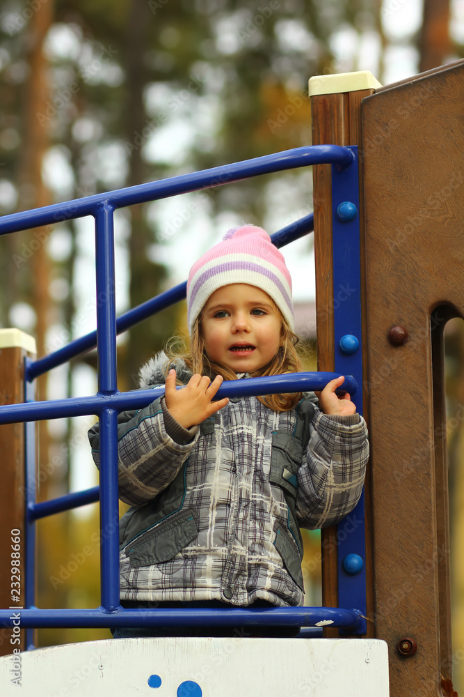 Portrait of a toddler girl playing in the autumn park, looking in the distance Portrait of a toddler girl playing in the autumn park, looking in the distance