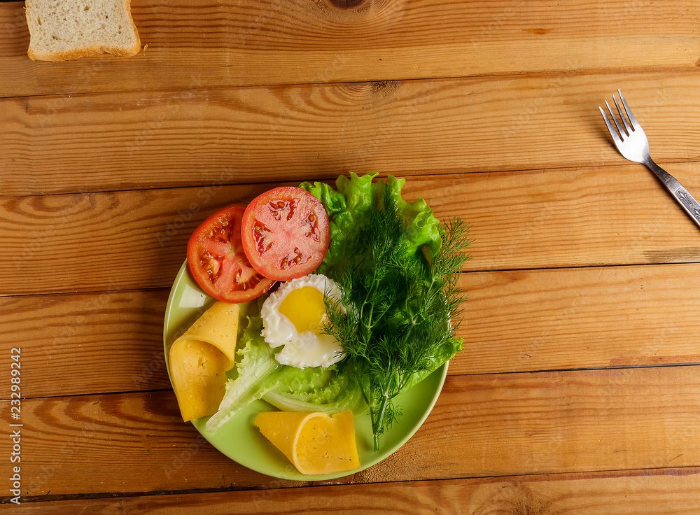 Fried eggs, pieces of vegetables, bread and fork on the table. Fried eggs, pieces of vegetables, bread and fork on the table.