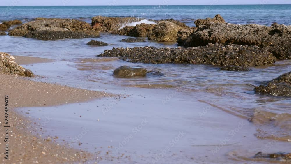 Ocean waves gentling lapping on sandy and rocky beach Ocean waves gentling lapping on sandy and rocky beach