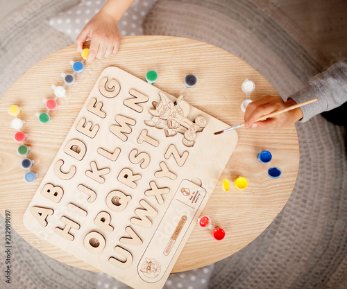 Children's wooden alphabet lies on the table next to the children.