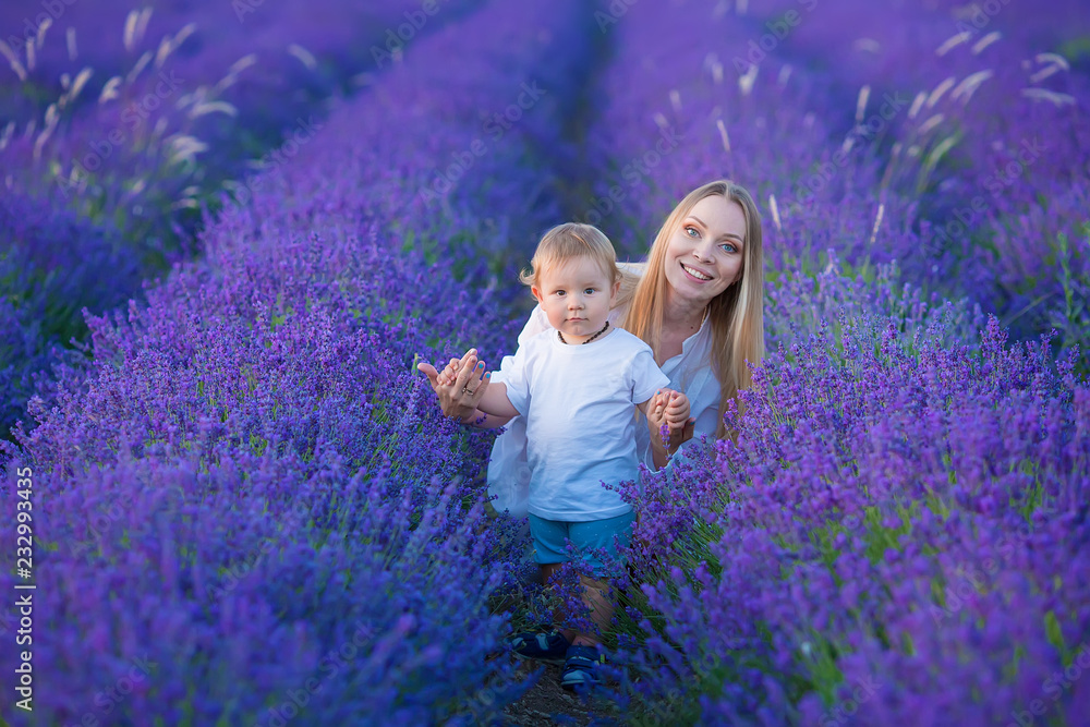 Happy mom with cute son on lavender background. Beautiful woman and boy in meadow field. Lavender landscape with lady and kid enjoying aroma and vivid colors. Family picture in colorful lavender view Happy mom with cute son on lavender background. Beautiful woman and boy in meadow field. Lavender landscape with lady and kid enjoying aroma and vivid colors. Family picture in colorful lavender view