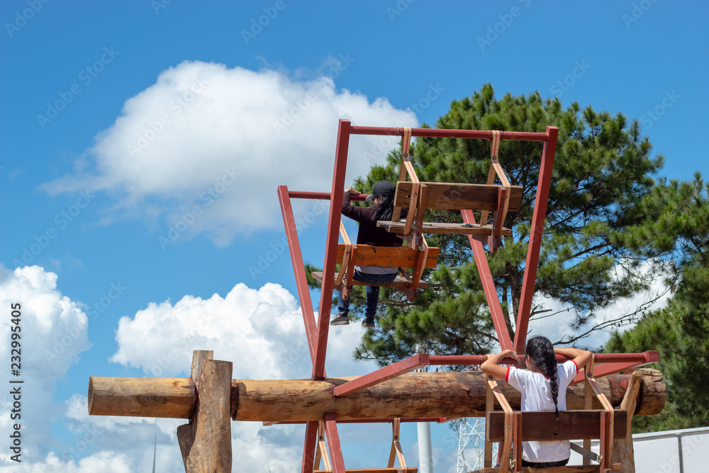 Women ride the wooden Ferris wheel and bright blue sky at Windtime Khao kho , Phetchabun in Thailand. Women ride the wooden Ferris wheel and bright blue sky at Windtime Khao kho , Phetchabun in Thailand.