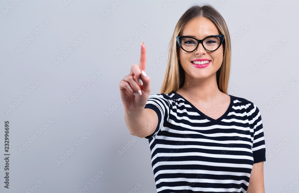 Young woman pointing at something on a gray background Young woman pointing at something on a gray background