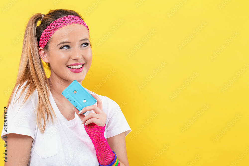 Woman in 1980's fashion holding a cassette tape on a yellow background